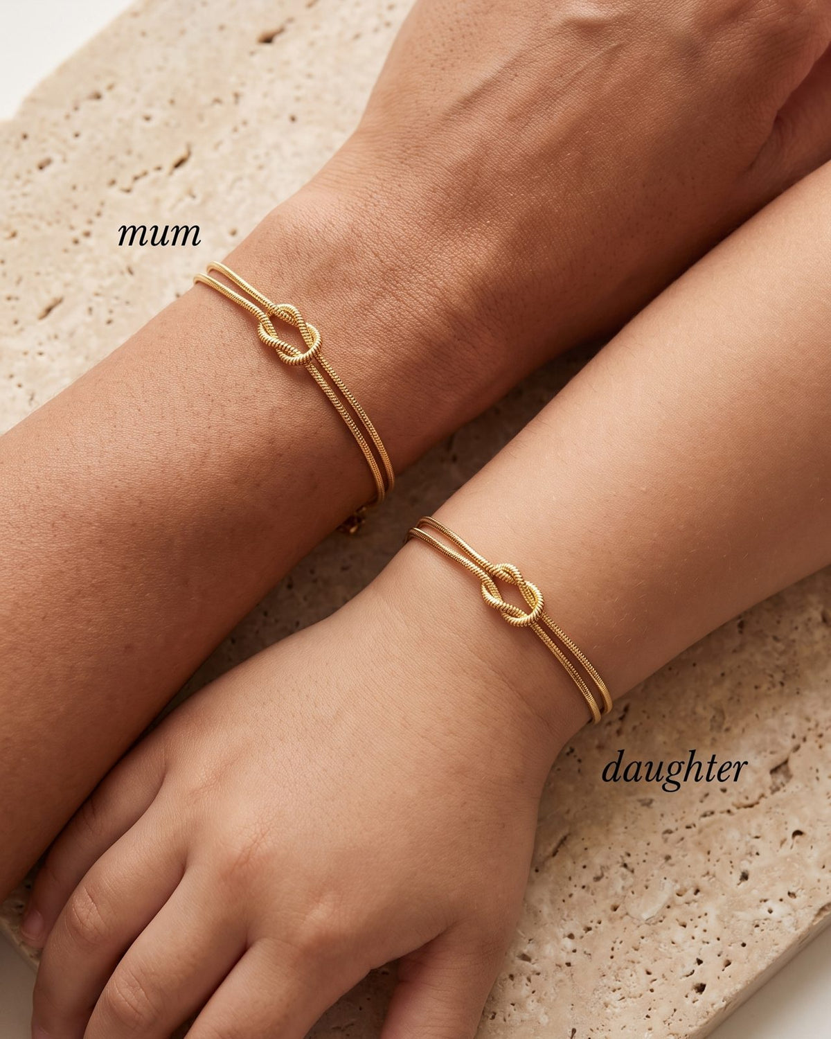 Mother and daughter wrists wearing matching gold knot bracelets
